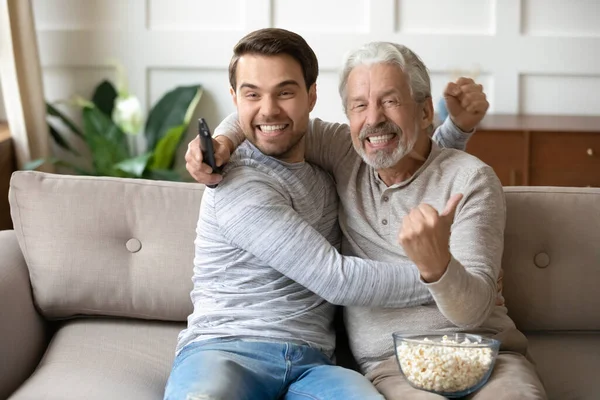 Волнующий мужчина со взрослым отцом смотрит футбольный матч — стоковое фото