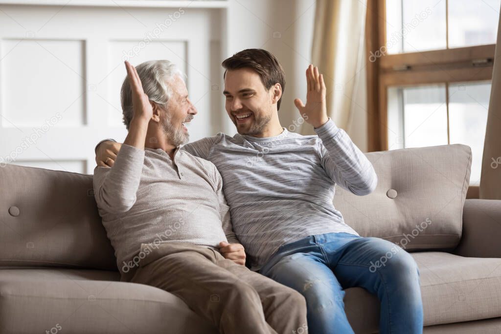 Overjoyed elderly dad and adult son give high five