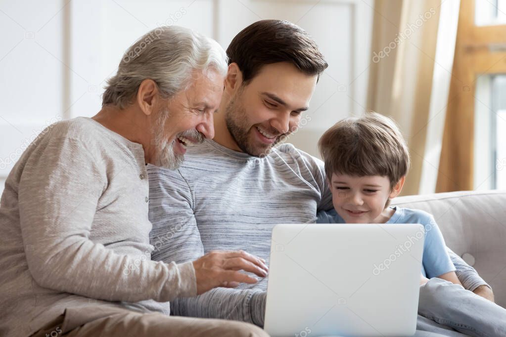 Smiling three generations of men use laptop together