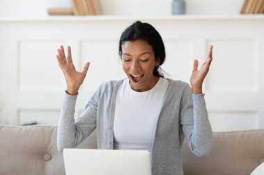 Genç mutlu Afrikalı etnik kadın dizüstü bilgisayara bakıyor..