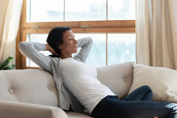 Tranquil joven africana americana biracial mujer relajarse en cómodo sofá. — Foto de Stock