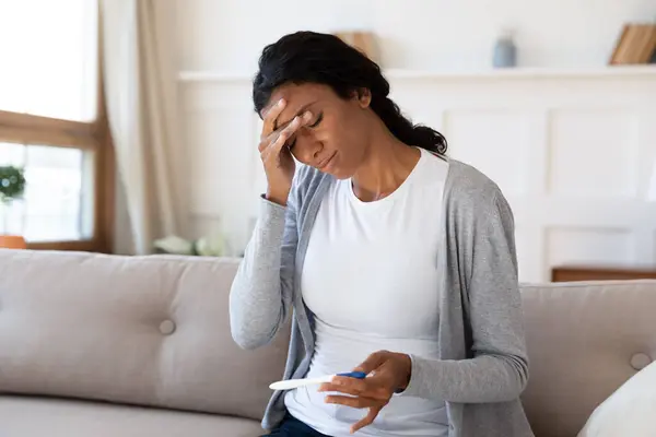 Frustrerad ung afrikansk amerikansk kvinna tittar på graviditetstest. — Stockfoto