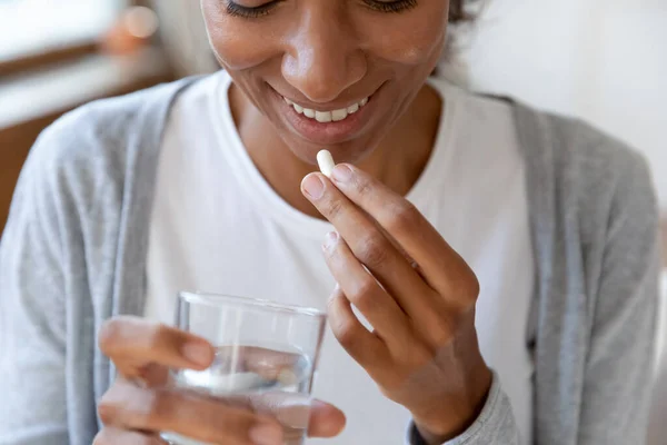 Gros plan jeune femme afro-américaine heureuse prenant des vitamines. — Photo