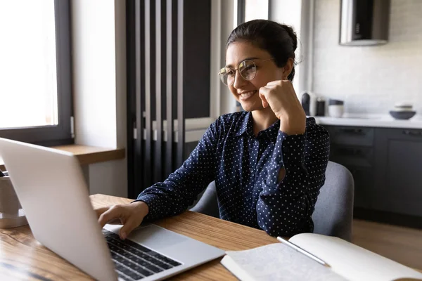 戴着眼镜微笑的印度女人在笔记本电脑上工作 — 图库照片