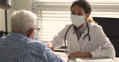 Kardiyolog yaşlı bir hastayla yüz maskesi takıyor.