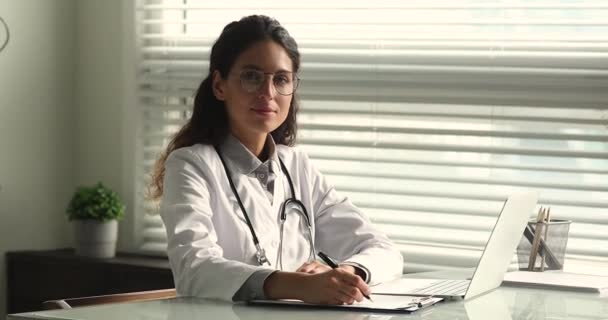 Fiatal magasan képzett háziorvos női orvos a klinika irodájában — Stock videók
