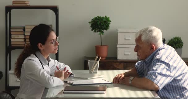 Квалифицированный практикующий врач поговорит со старшим пациентом в клинике — стоковое видео