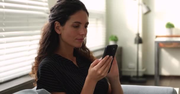 Žena odpočívá na gauči trávit volný čas pomocí chytrého telefonu — Stock video