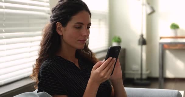 Mujer descansando en el sofá pasar el ocio utilizando el teléfono inteligente — Vídeos de Stock