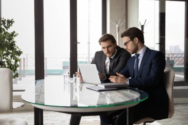 Erkek meslektaşlar internette dizüstü bilgisayarda çalışıyor