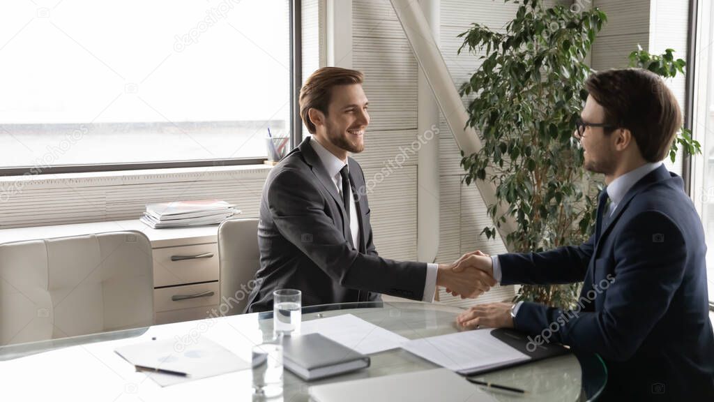 Smiling businessmen handshake at business meeting in office