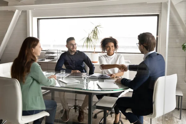 Smiling multiracial colleagues handshake get acquainted at meeting