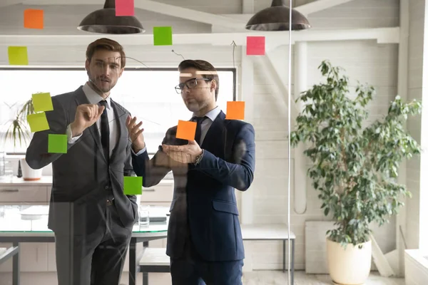 Male colleagues brainstorm develop business plan in boardroom