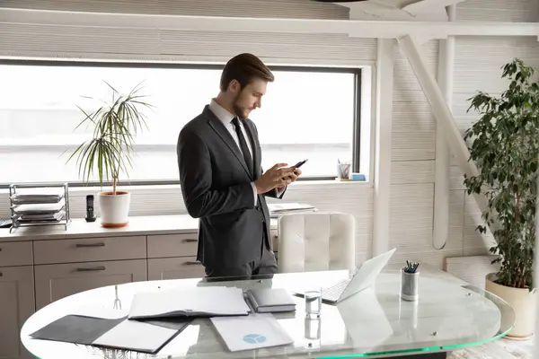 Jovem empresário caucasiano usa celular moderno no escritório — Fotografia de Stock