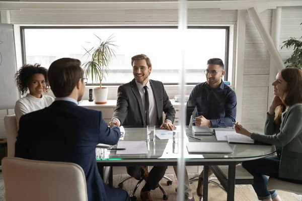 Hombres de negocios sonrientes se dan la mano cerrando trato en la reunión — Foto de Stock