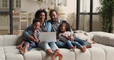 Genç Afrikalı çiftler dizüstü bilgisayarlarıyla kanepede dinleniyorlar.