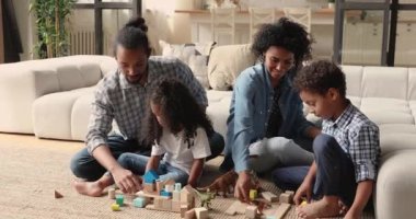 Çocuklu Afrikalı aileler dinozor oyuncakları ve tahta tuğlalarla oynuyorlar.