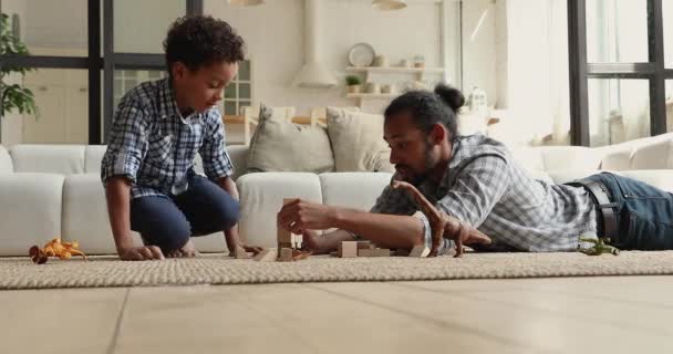 Op de vloer Afrikaanse jongen spelen houten blokken met papa — Stockvideo