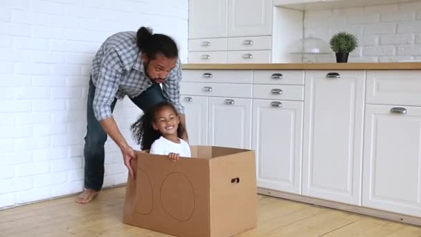 Father riding daughter while she sitting inside of cardboard box — Stock Video