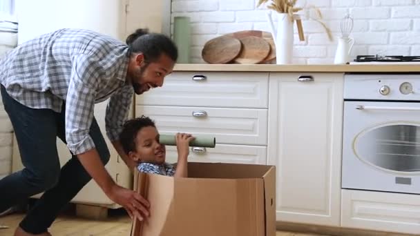 Ojciec ujeżdżający syna, gdy siedzi w kartonowym pudełku. — Wideo stockowe