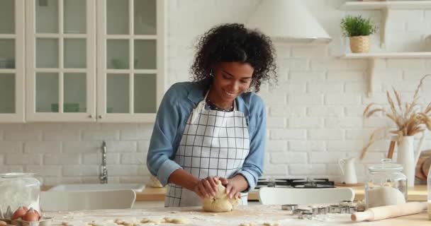 Mujer africana usa delantal amasando masa preparando galletas en la cocina — Vídeos de Stock