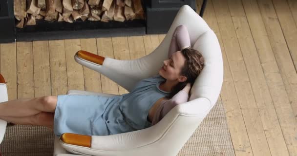 Femme sereine mettre les mains derrière la tête relaxant sur fauteuil confortable — Video