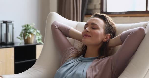 Attractive woman closed eyes relaxing leaned on comfortable armchair indoor — Stock Video