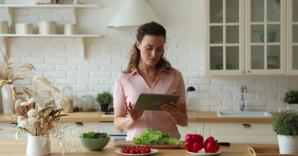 Молодая женщина держит планшет устройство поиска здоровой пищи рецепты онлайн — стоковое видео