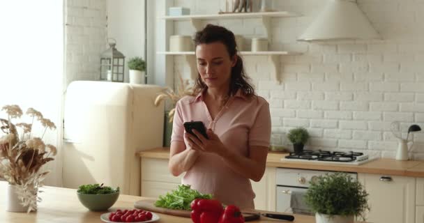 Νεαρή γυναίκα κρατώντας smartphone αναζήτηση υγιεινά χορτοφαγικές συνταγές τροφίμων σε απευθείας σύνδεση — Αρχείο Βίντεο