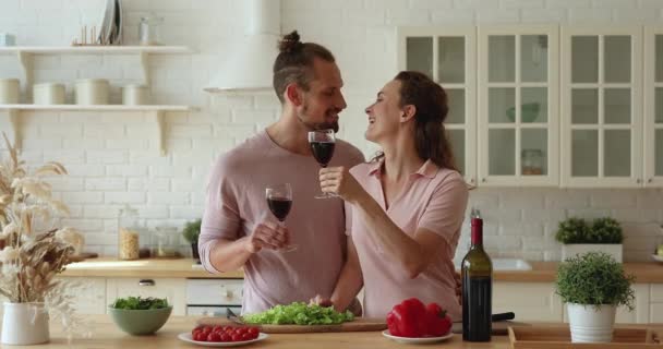 Paar drinken rode wijn zoenen genieten romantisch date in keuken — Stockvideo