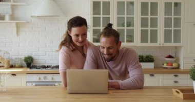 Genç çift mutfakta dizüstü bilgisayarla vakit geçiriyor.