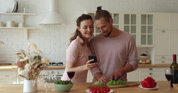 Vrouw show naar man recept op smartphone terwijl hij koken — Stockvideo