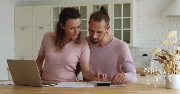 Ungt ektepar forvalter familiebudsjettet med regninger og kalkulator – stockvideo