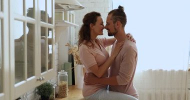 Genç ve çekici bir çift ev mutfağında öpüşüyor.