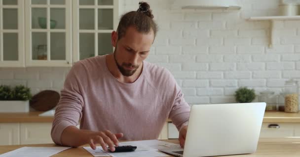 Hombre calcula los gastos de gestión de presupuesto personal utilizando calculadora y portátil — Vídeos de Stock