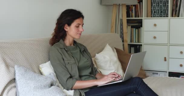 Avslappet ung, lykkelig kvinne som bruker datamaskin hjemme. – stockvideo