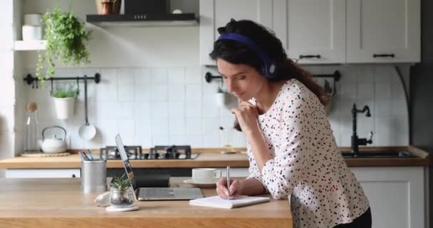 Lachende mooie jonge vrouwelijke student studeren op afstand in de keuken. — Stockvideo