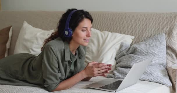 Jonge glimlachende vrouw met videogesprek, liggend op de bank. — Stockvideo