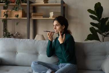 Genç kadın hoparlörde akıllı telefondan konuşuyor.