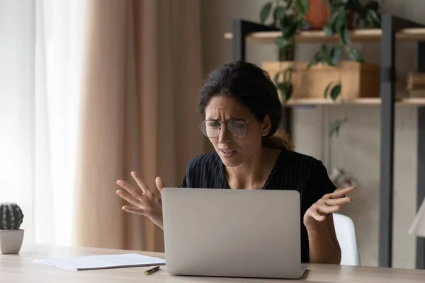 Upset young woman confused by laptop problems