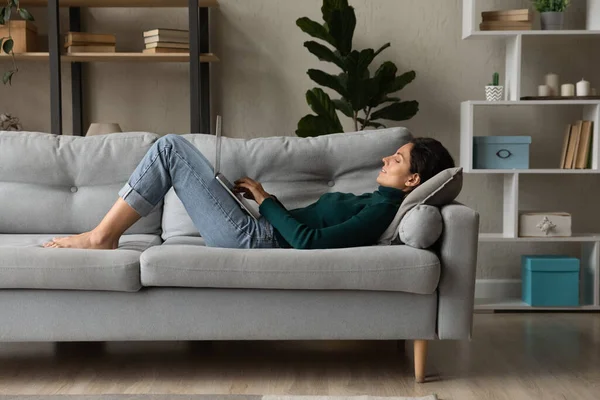 Jeune femme couchée sur le canapé travaillant en ligne sur ordinateur portable — Photo