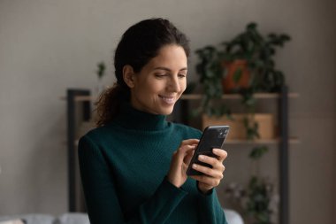 Gülümseyen kadın internette akıllı telefon aygıtı kullanıyor.