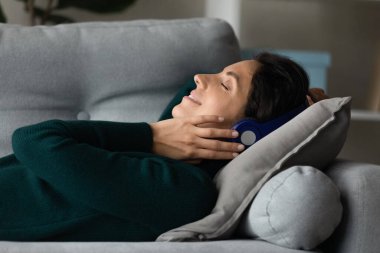 Mutlu genç kadın kulaklıkla müzik dinliyor.