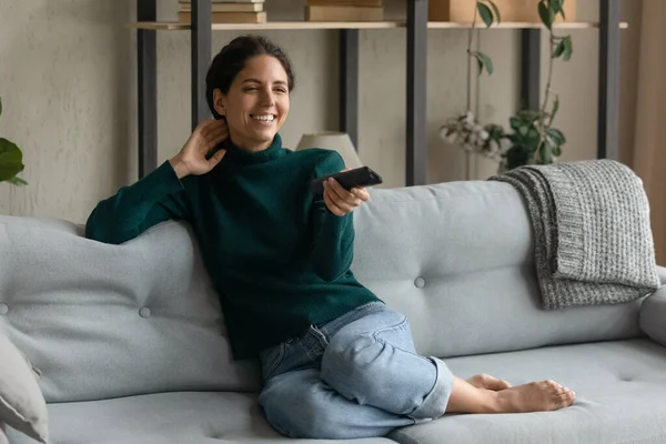 Sorrindo mulher relaxar no sofá assistindo TV — Fotografia de Stock