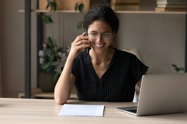 Smiling woman work on computer talk on cellphone — Stock Photo, Image