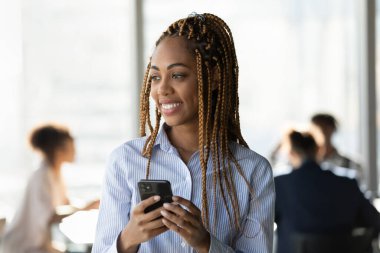 Gülümseyen etnik kadın ofiste cep telefonu kullanıyor