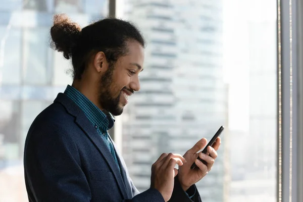 Sorrindo homem afro-americano usar mensagens de texto smartphone on-line — Fotografia de Stock