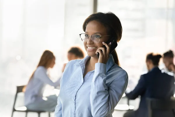 Gülümseyen Afrikalı Amerikalı kadın müşteriyle akıllı telefonda konuşuyor. — Stok fotoğraf
