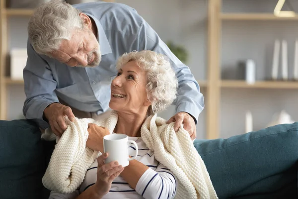 Hombre mayor cariñoso cubriendo hombros de esposa sonriente con cuadros. — Foto de Stock