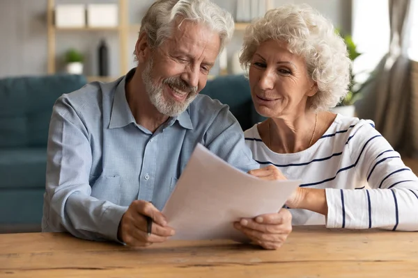 Feliz pareja de ancianos leyendo el documento en papel. —  Fotos de Stock